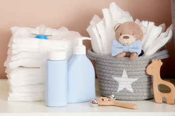A stack of diapers, toys and baby accessories on a changing table.