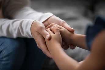 An adult and a child hold hands.