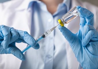 Hand holding syringe and vaccine.