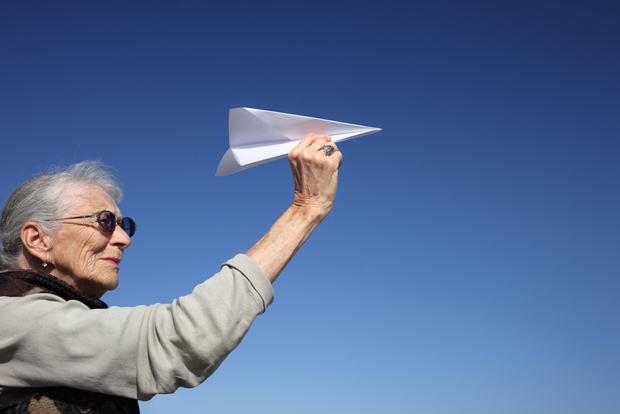 Happy older lady playing with paper plane Happy older lady playing with paper plane