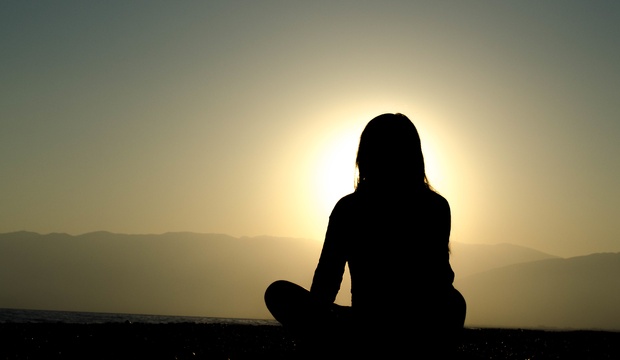 Woman meditating at sunset Woman meditating at sunset