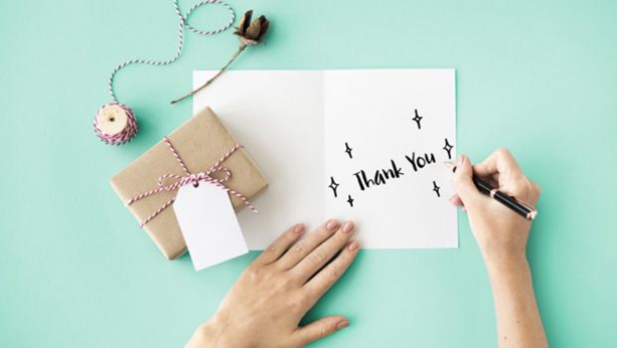 A woman writes thank you on a card