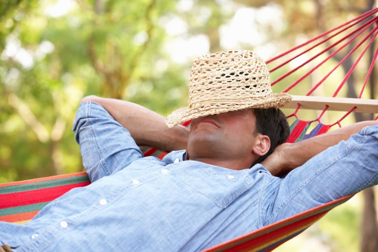 Man relaxing in hammock with hat covering his face Man relaxing in hammock with hat covering his face