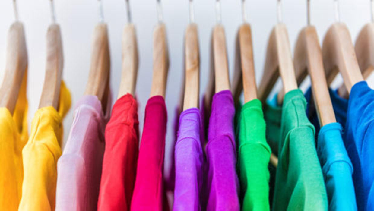 Shirts in different colors hang in a closet. Shirts in different colors hang in a closet.