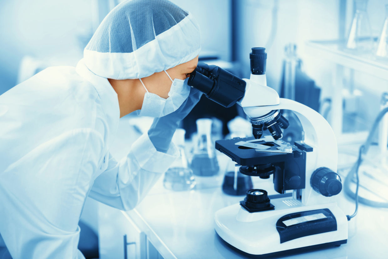Young woman medical researcher looking through microscop slide in the life science Young woman medical researcher looking through microscop slide in the life science