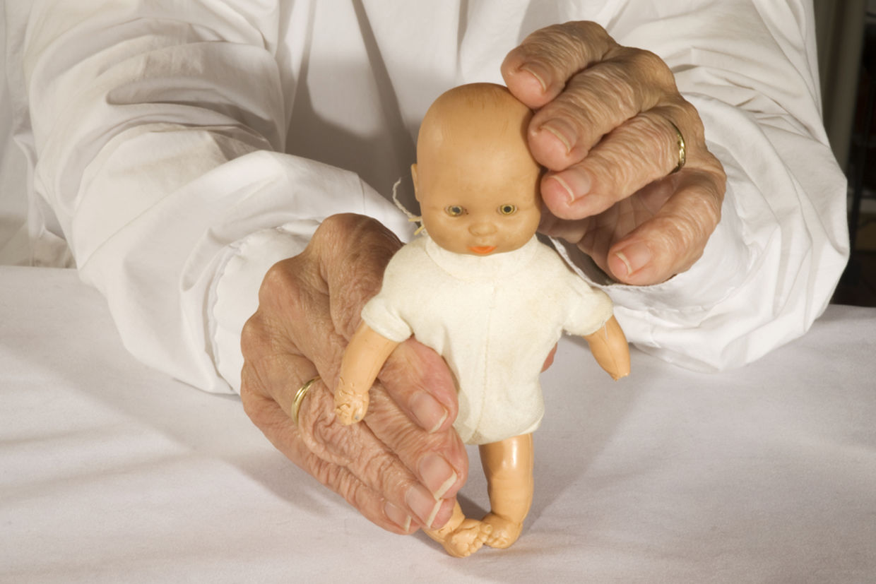Old demented person plays with toy doll Old demented person plays with toy doll