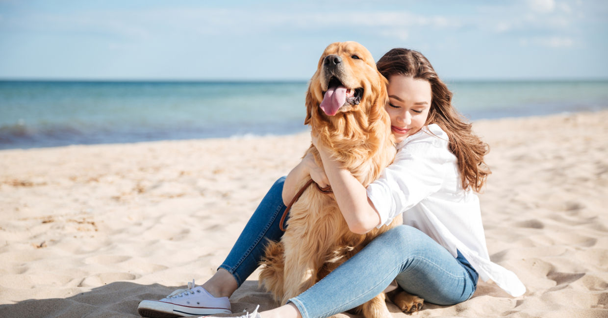 Woman sitting with dog on beach Woman sitting with dog on beach