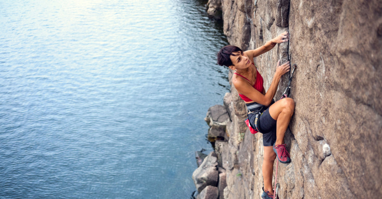 take a risk - Female climber dangles from the edge of a challenging cliff take a risk - Female climber dangles from the edge of a challenging cliff