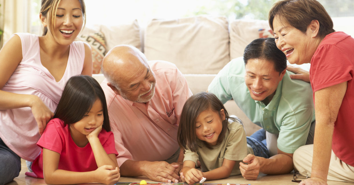 A family laughs while playing a board game. A family laughs while playing a board game.