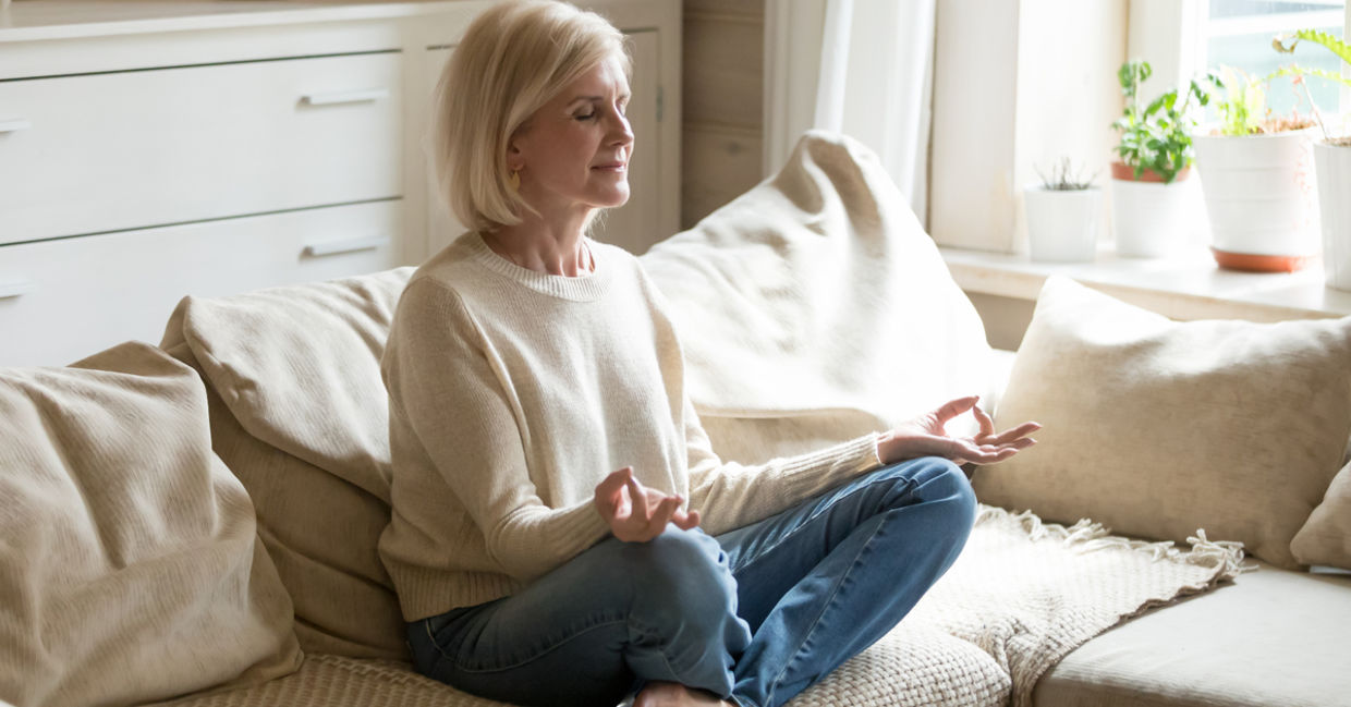 A woman meditates on her couch. A woman meditates on her couch.