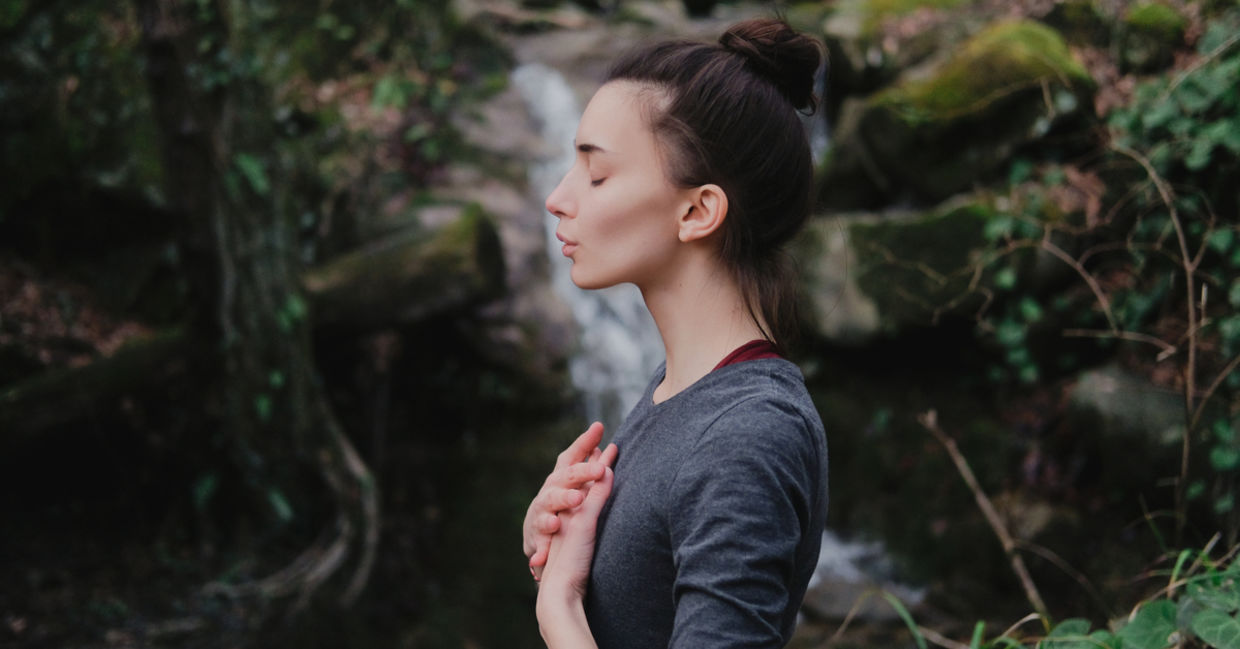 A woman practicing breathing in a forest. A woman practicing breathing in a forest.