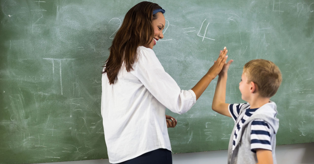 A teacher gives a student a high five. A teacher gives a student a high five.