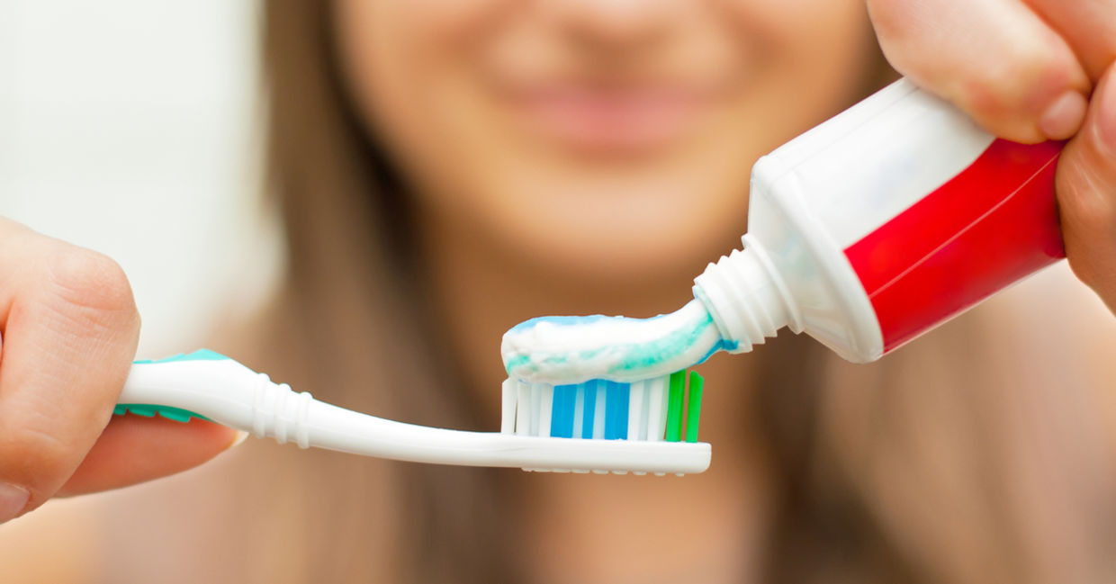 Woman putting toothpaste on a toothbrush. Woman putting toothpaste on a toothbrush.