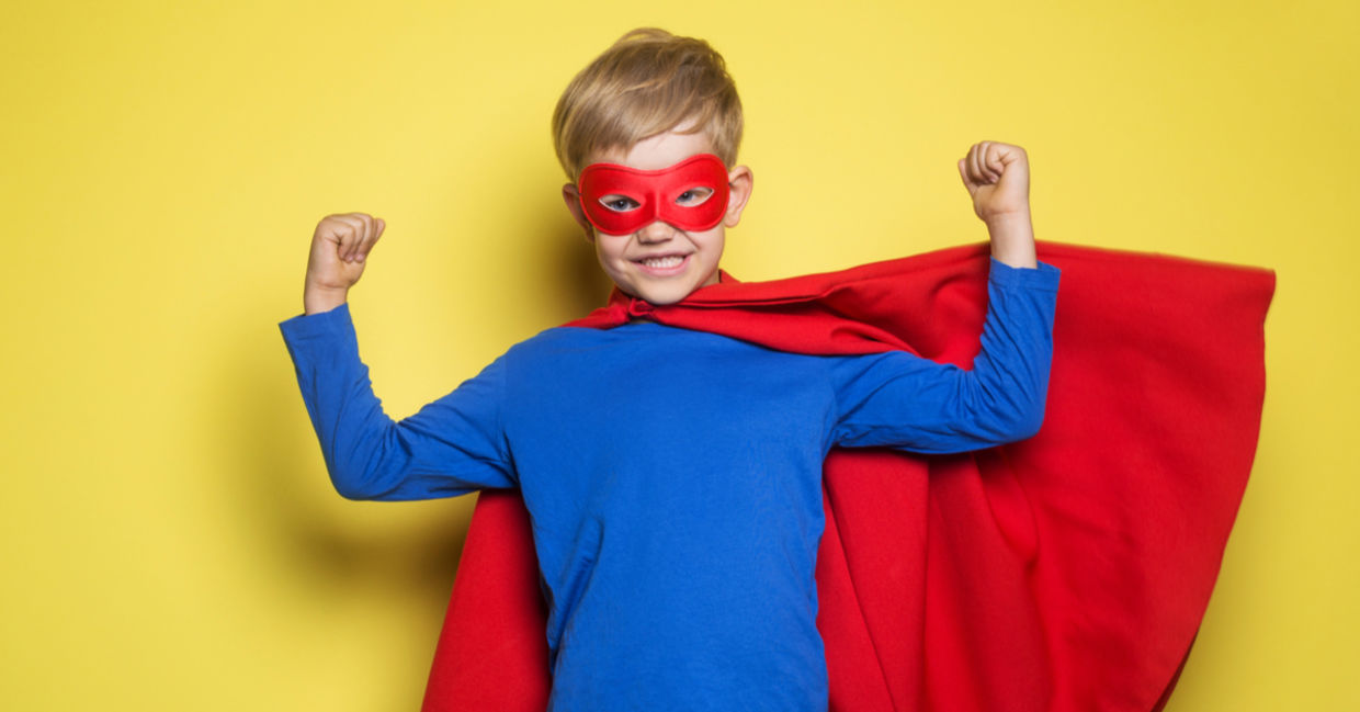 A young boy wearing a superhero mask and cape flexes his muscles and feels strong. A young boy wearing a superhero mask and cape flexes his muscles and feels strong.
