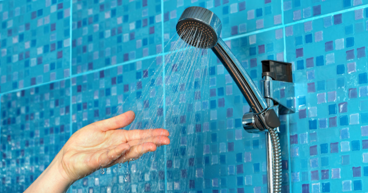 A woman checks the water flow on her reduced, low-flow shower faucet. A woman checks the water flow on her reduced, low-flow shower faucet.