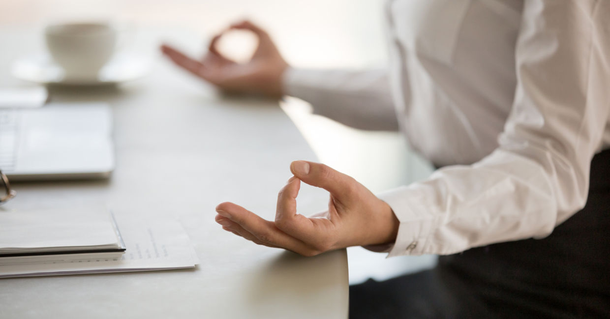 A man practices mindfulness at work by meditating at his desk. A man practices mindfulness at work by meditating at his desk.