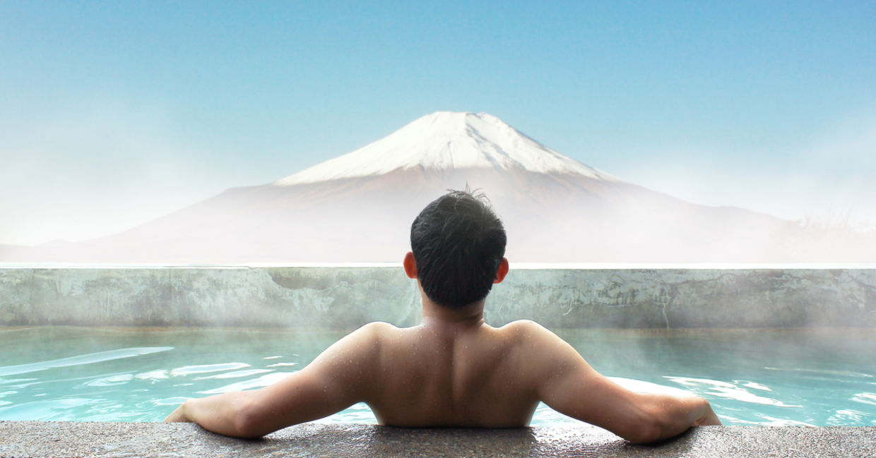 A Japanese man soaking in a hot spring gazes out at Mt. Fuji. A Japanese man soaking in a hot spring gazes out at Mt. Fuji.