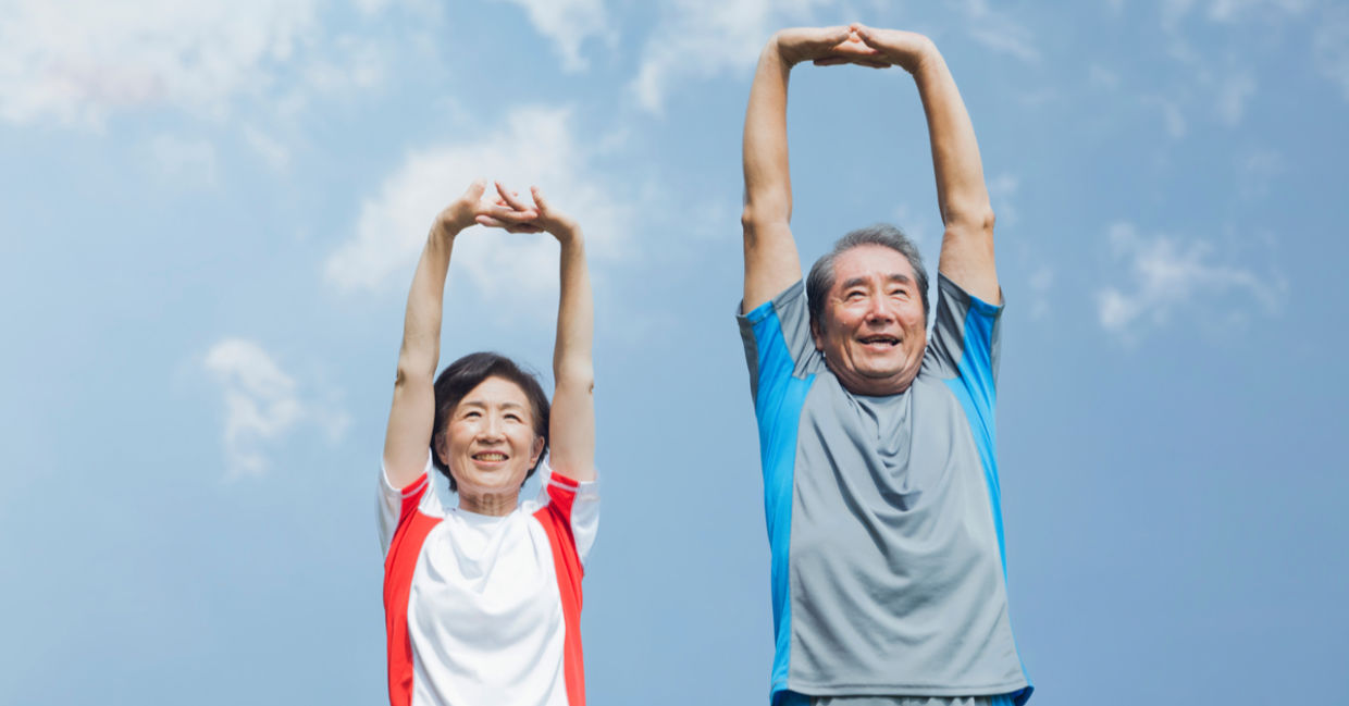 Older Japanese couple stretching under a blue sky. Older Japanese couple stretching under a blue sky.