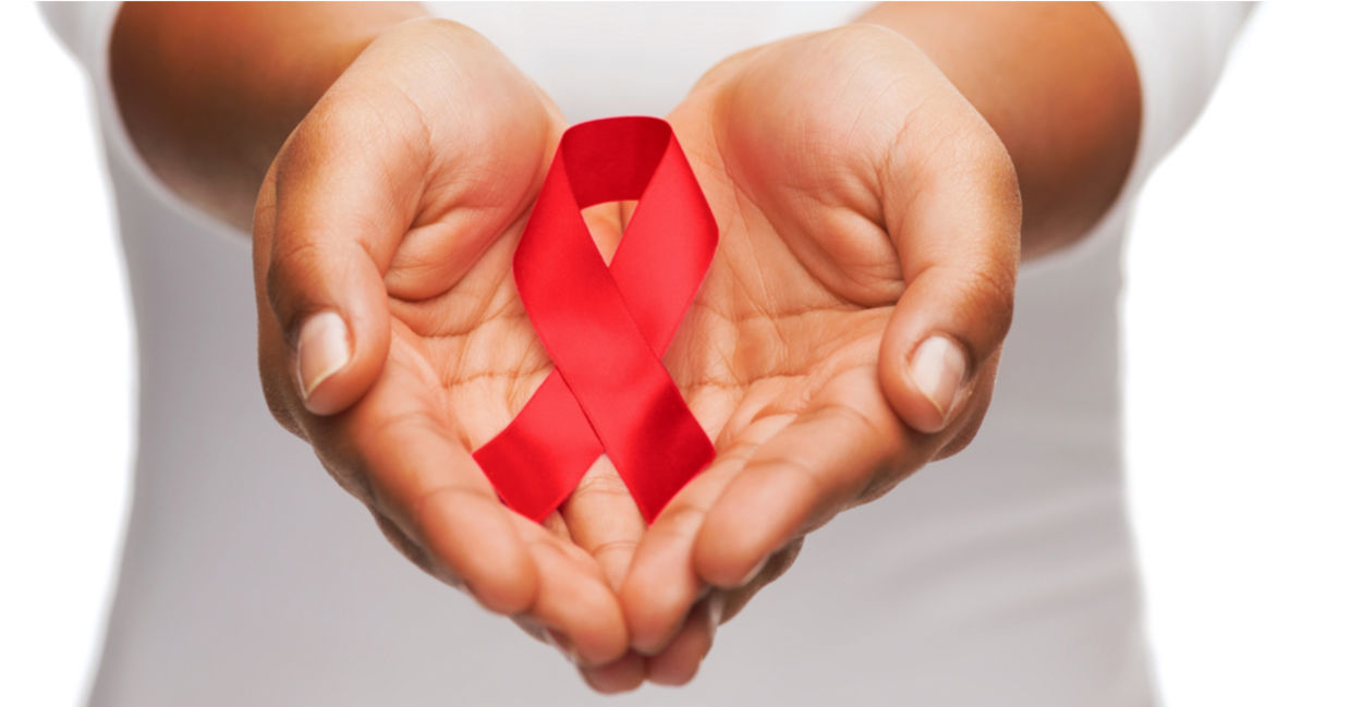 AIDS awareness ribbon in between two hands. AIDS awareness ribbon in between two hands.
