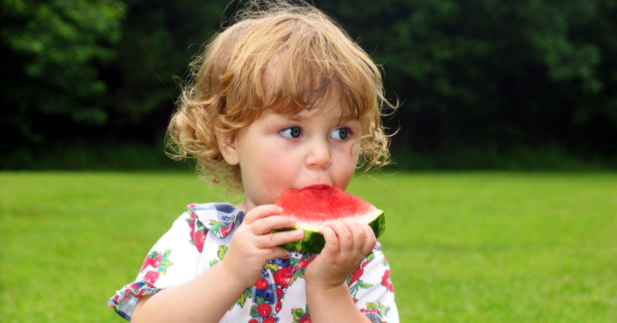 Little girl taking a bite out of watermelon wedge Little girl taking a bite out of watermelon wedge
