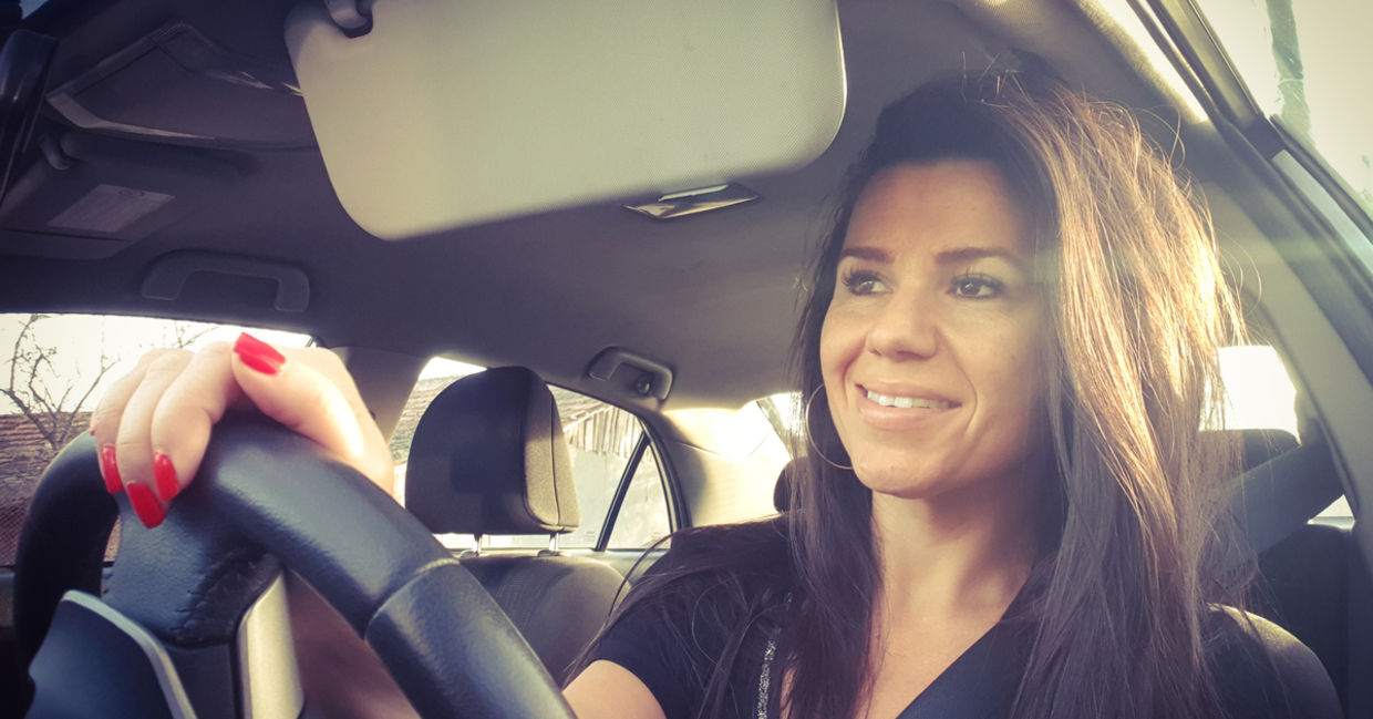 A woman smiling from her car in traffic. A woman smiling from her car in traffic.