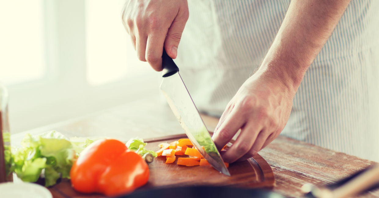 A person chopping vegetables on a wooden cutting board. A person chopping vegetables on a wooden cutting board.
