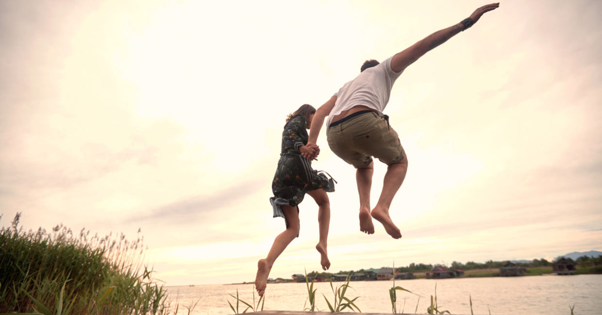 A young couple spontaneously jumps into a river. A young couple spontaneously jumps into a river.