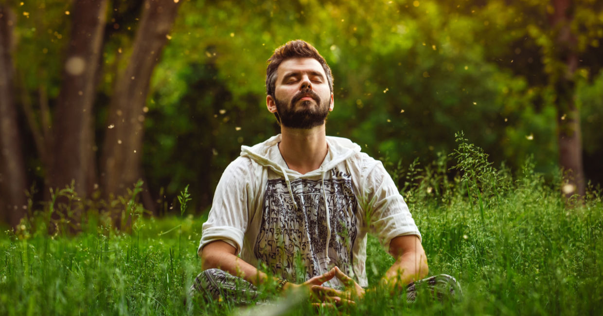 A young man meditates in a sunny meadow. A young man meditates in a sunny meadow.