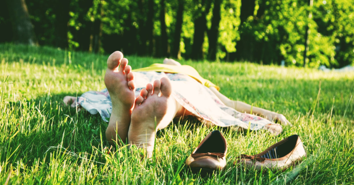 A woman sleeping barefoot on the grass. A woman sleeping barefoot on the grass.