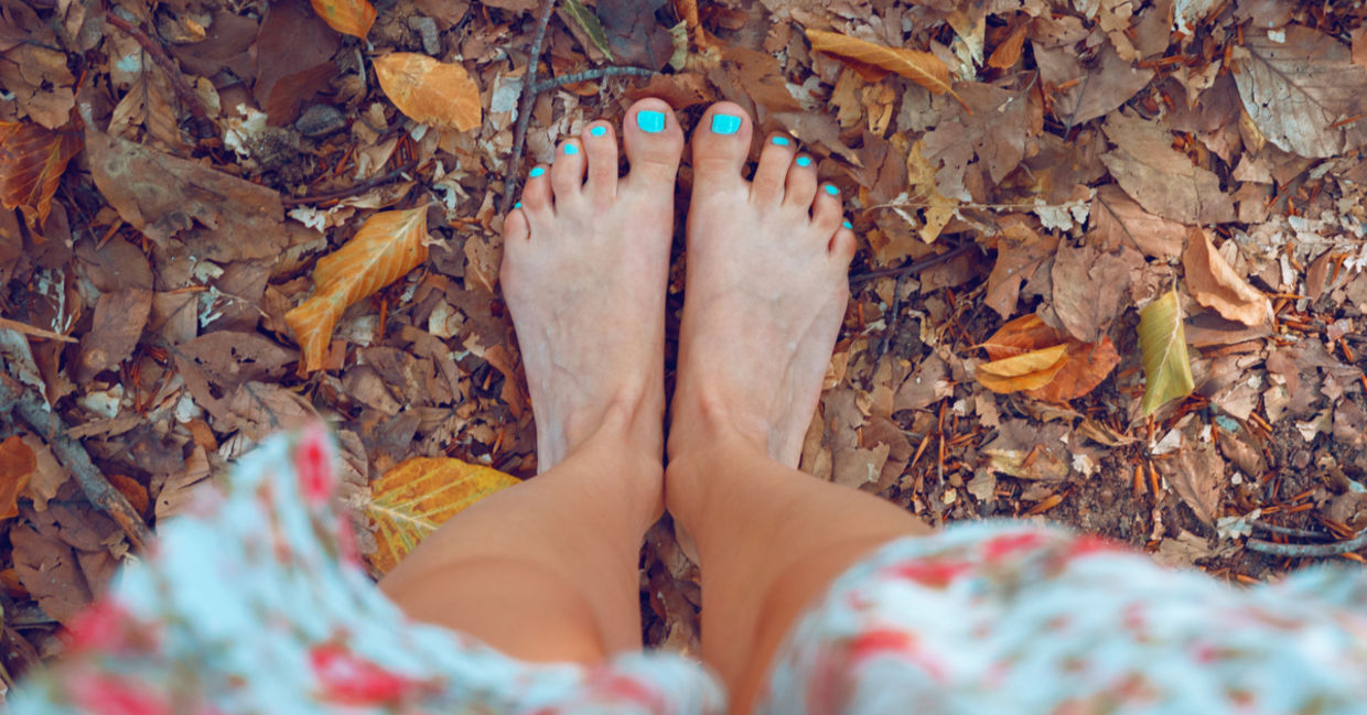A woman stands barefoot on autumn leaves. A woman stands barefoot on autumn leaves.
