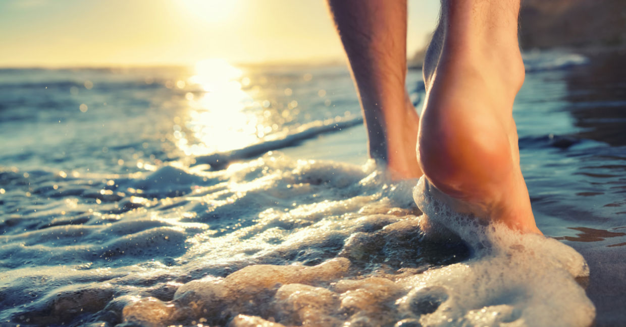 A man takes a sunset walk, barefoot, in the foaming waves. A man takes a sunset walk, barefoot, in the foaming waves.