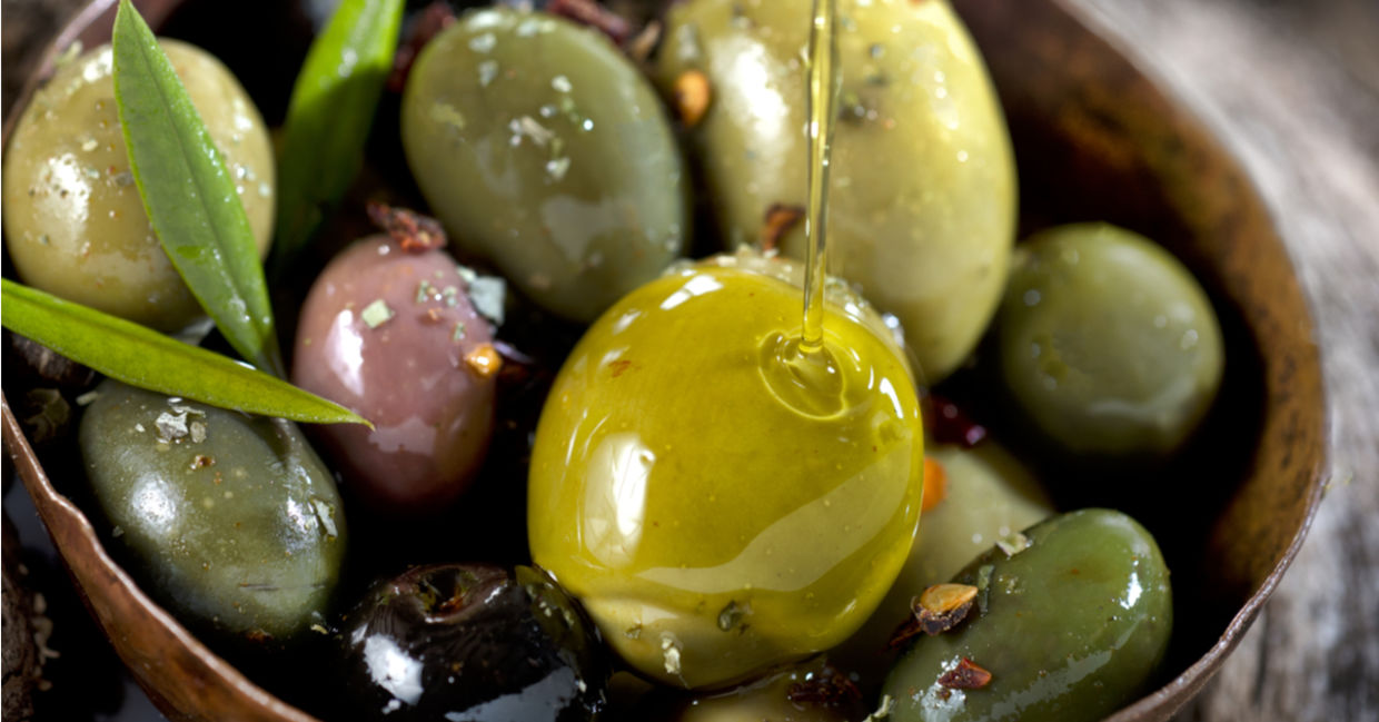 A wooden bowl filled with shiny olives. A wooden bowl filled with shiny olives.