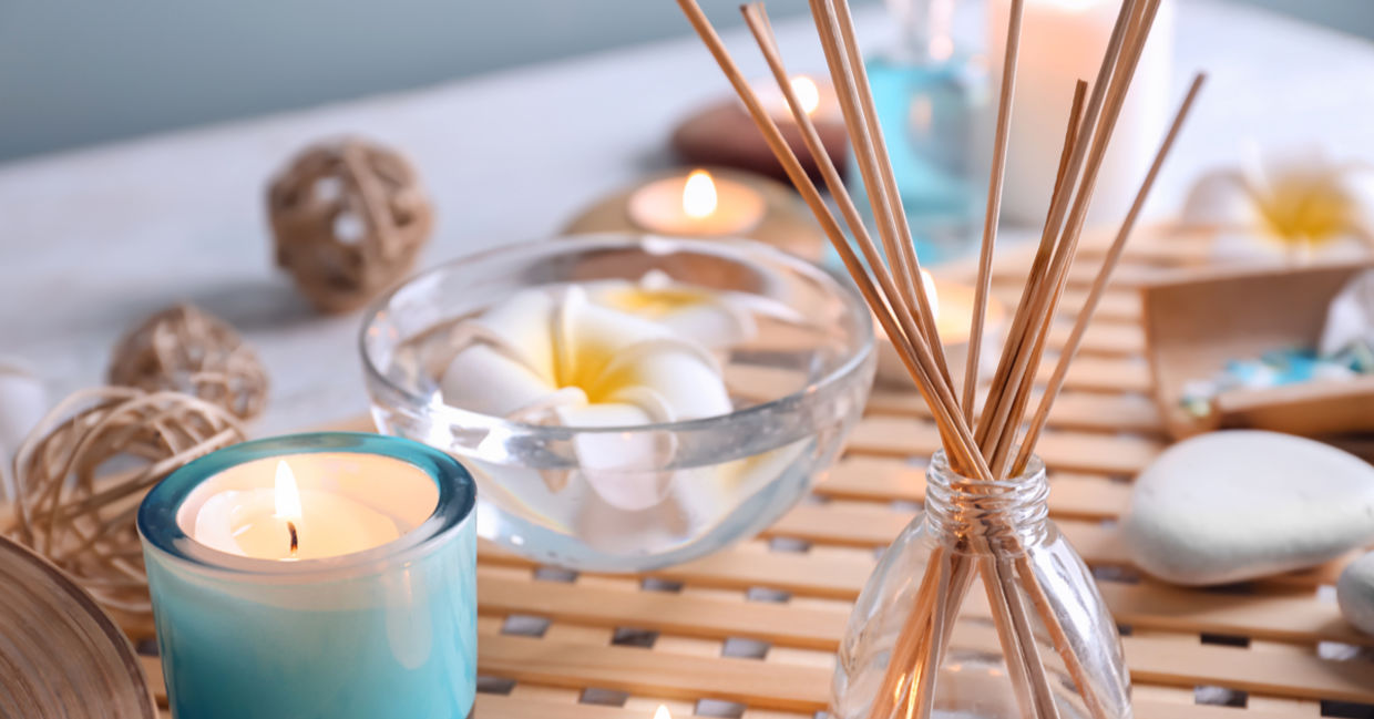 Diffuser reeds in a bottle beside tea lights and flowers. Diffuser reeds in a bottle beside tea lights and flowers.
