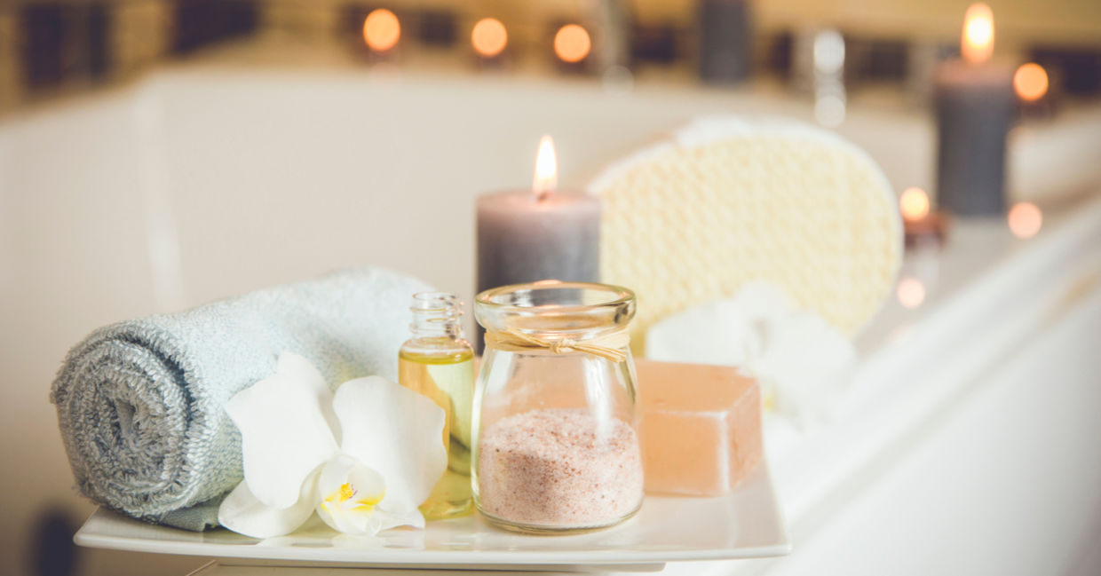Home spa with rolled towel, bath oil, and candles. Home spa with rolled towel, bath oil, and candles.