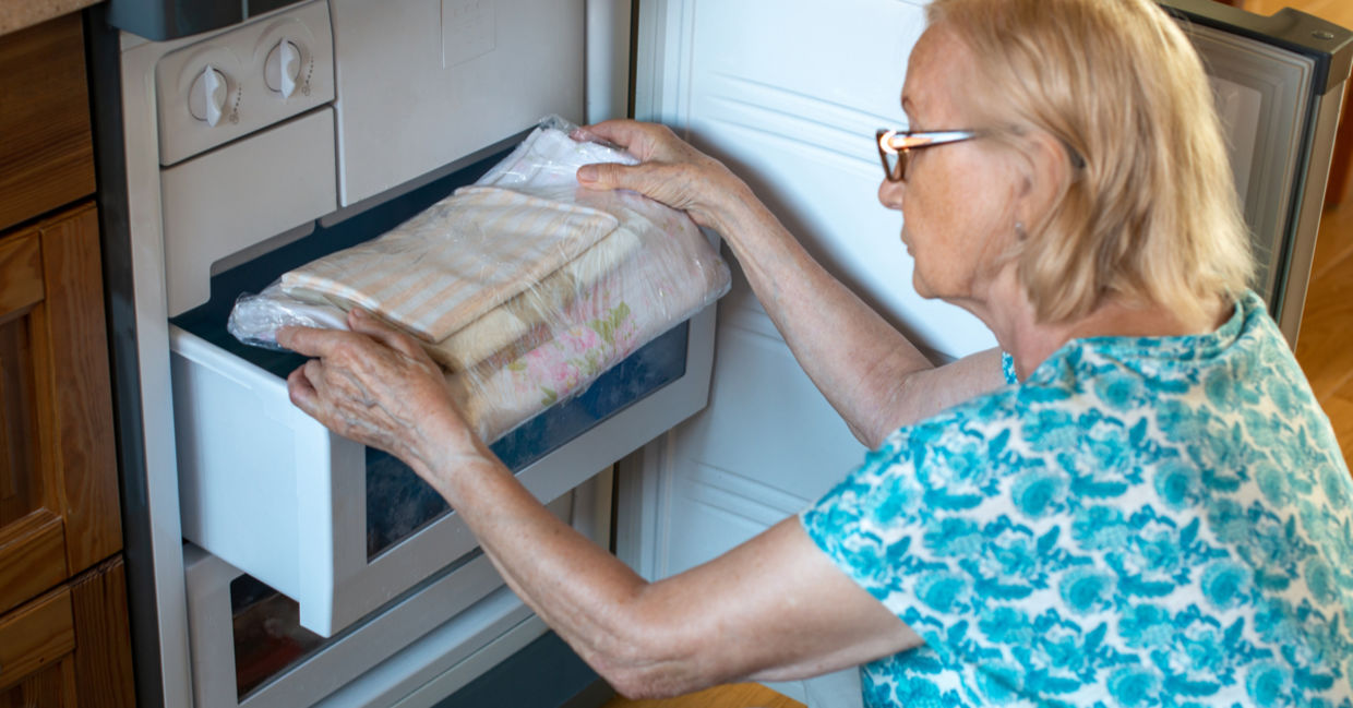 Woman putting bed clothes in the fridge freezer to stay cool in hot weather Woman putting bed clothes in the fridge freezer to stay cool in hot weather