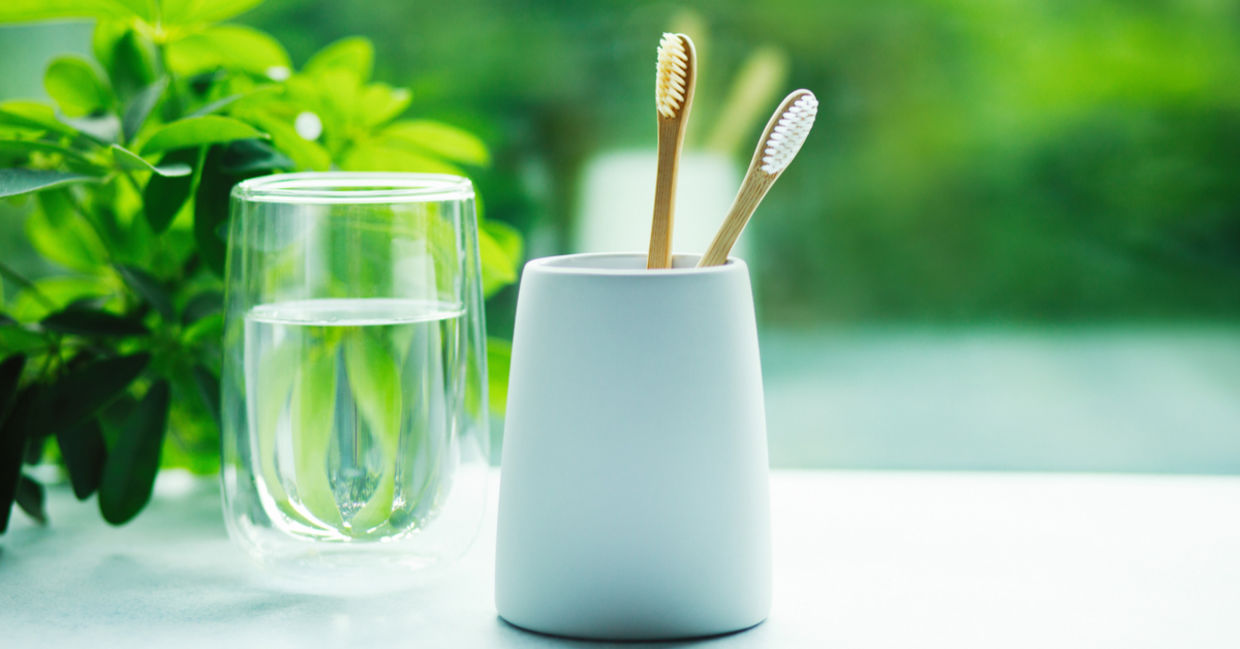 Bamboo toothbrushes in a cup and glass with water Bamboo toothbrushes in a cup and glass with water