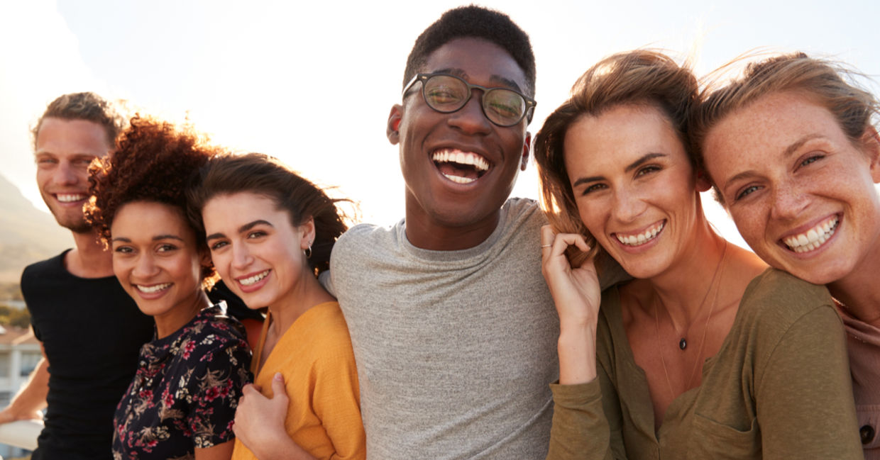 A group of young friends outside, smiling together. A group of young friends outside, smiling together.