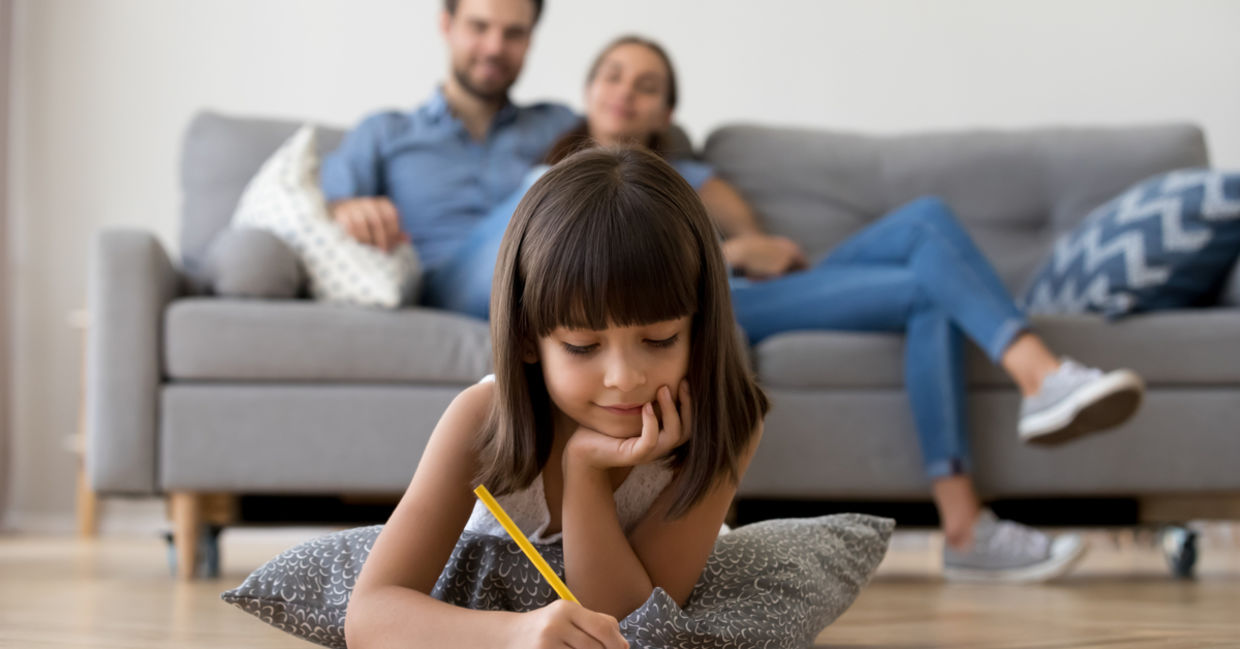 Cute kid drawing while her parents watch her from the sofa Cute kid drawing while her parents watch her from the sofa
