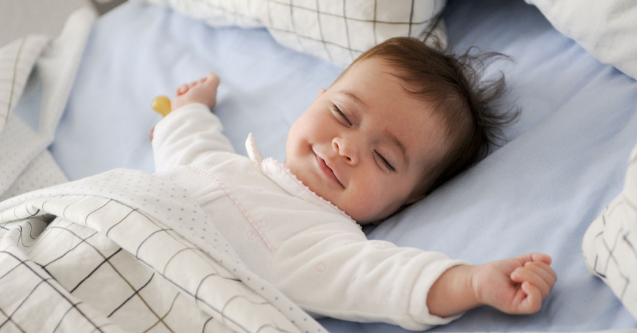 Smiling baby lying on a bed sleeping Smiling baby lying on a bed sleeping