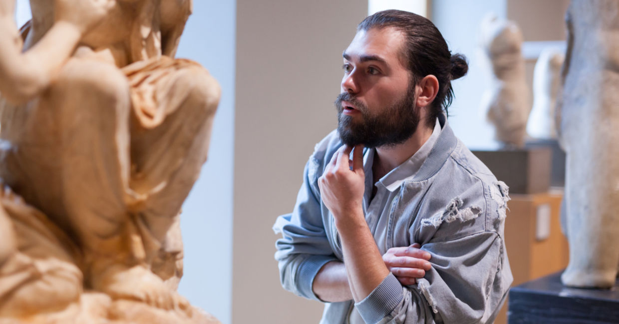 Man explores a sculpture in a museum. Man explores a sculpture in a museum.