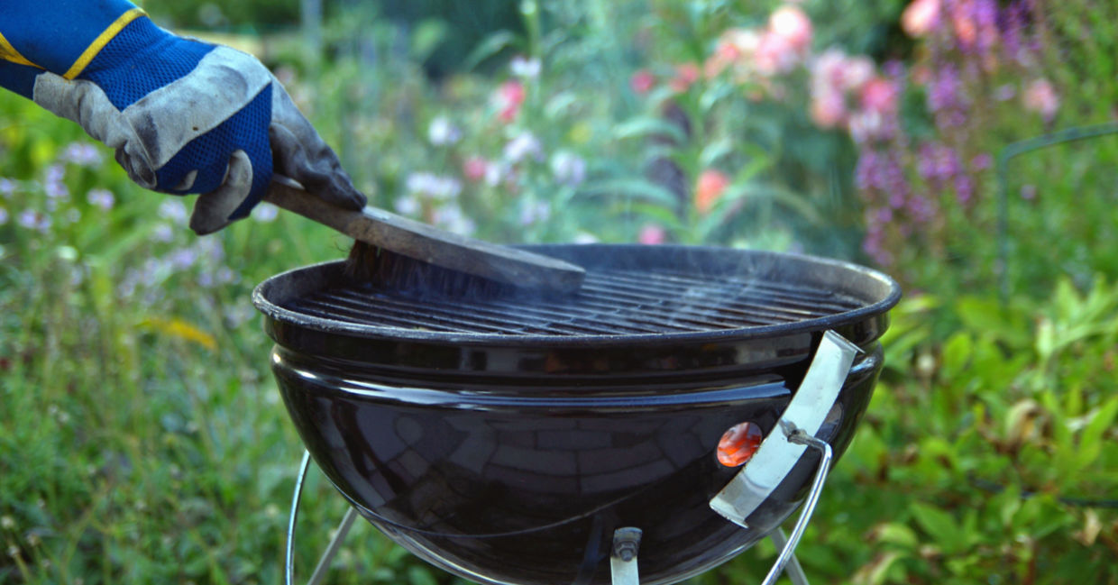 A man uses a grill brush to clean his barbecue. A man uses a grill brush to clean his barbecue.