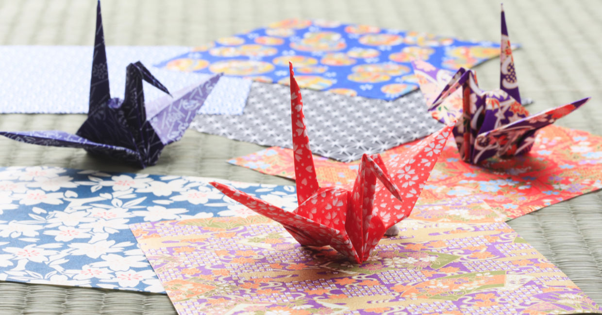Origami paper cranes perch on colorful paper. Origami paper cranes perch on colorful paper.