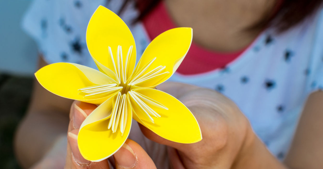 A girl holds a yellow origami flower. A girl holds a yellow origami flower.