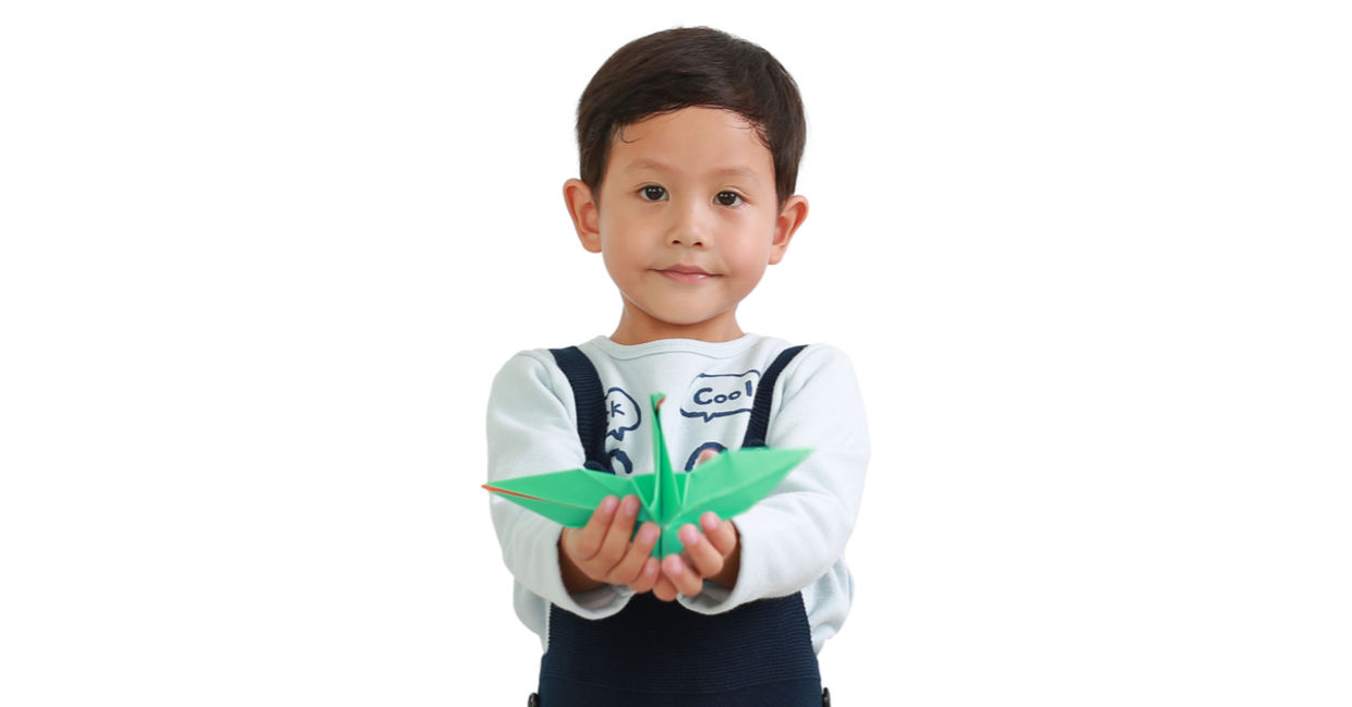 A little boy holds an origami bird. A little boy holds an origami bird.