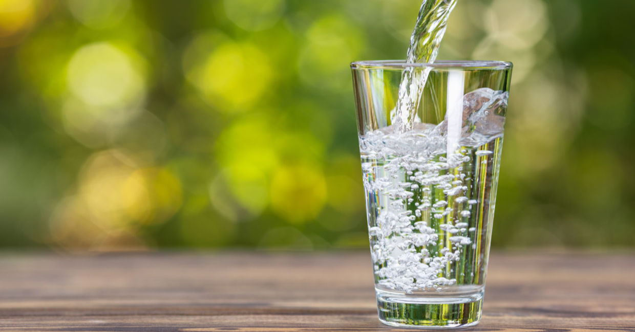 Drinking water from jug pouring into glass on wooden table outdoors Drinking water from jug pouring into glass on wooden table outdoors