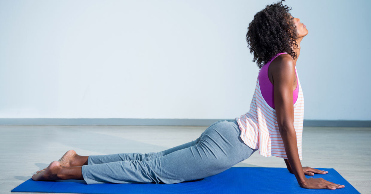 Woman doing cobra yoga pose on exercise mat in gym. Woman doing cobra yoga pose on exercise mat in gym.