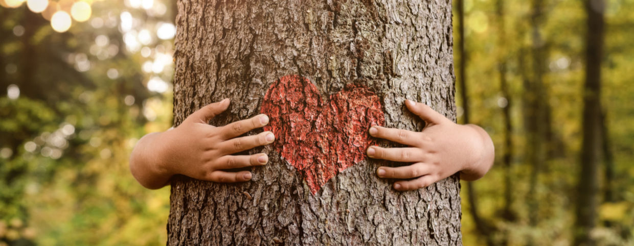 A plant empath hugs a tree with a heart painted on the trunk. A plant empath hugs a tree with a heart painted on the trunk.