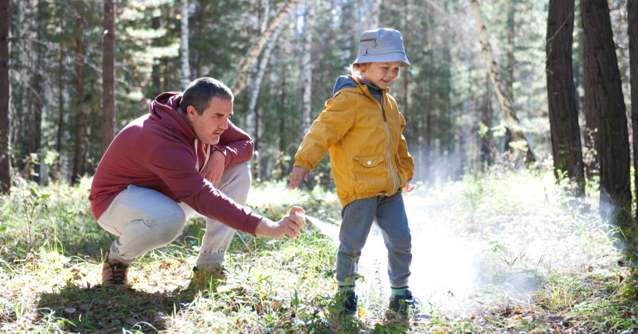 Dad using natural insect repellent made from tea tree oil on his son Dad using natural insect repellent made from tea tree oil on his son