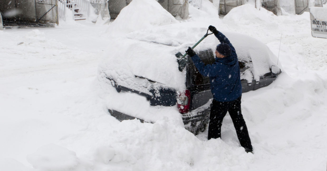 A man uses a shovel to dig his car out of deep snow. A man uses a shovel to dig his car out of deep snow.