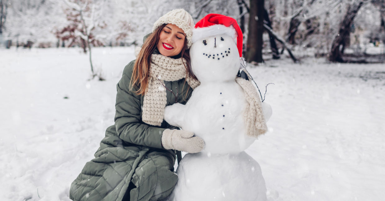 Happy to be outside in the cold winter, a woman hugs a snowman. Happy to be outside in the cold winter, a woman hugs a snowman.